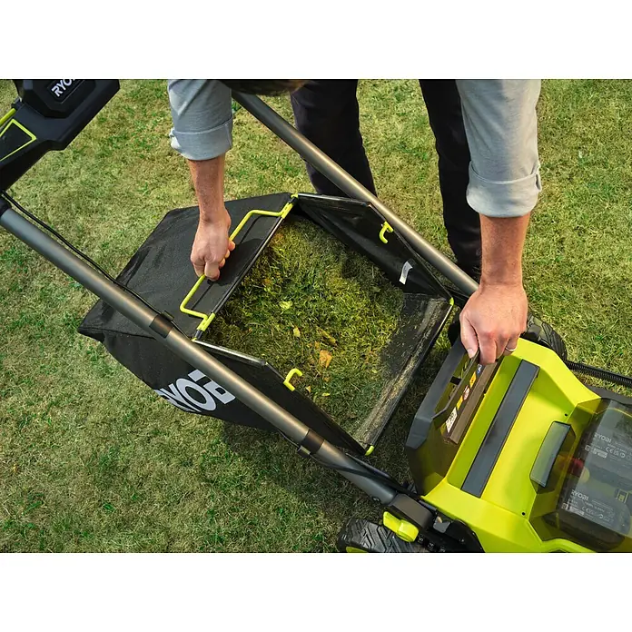 Ryobi ONE+ Akku-Rasenmäher RY18LMXSP51A - 18 V, Ohne Akku, Schnittbreite: 51 cm - Eine Person leert den schwarz-gelben Ryobi Rasenmäher-Fangkorb mit Grasschnitt.