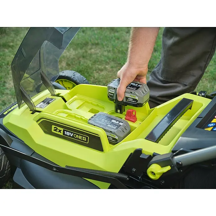 Ryobi ONE+ Akku-Rasenmäher RY18LMXSP51A - 18 V, Ohne Akku, Schnittbreite: 51 cm - Eine Person setzt einen grauen Ryobi 18V ONE+ Akku in einen leuchtend grünen Akku-Rasenmäher ein.