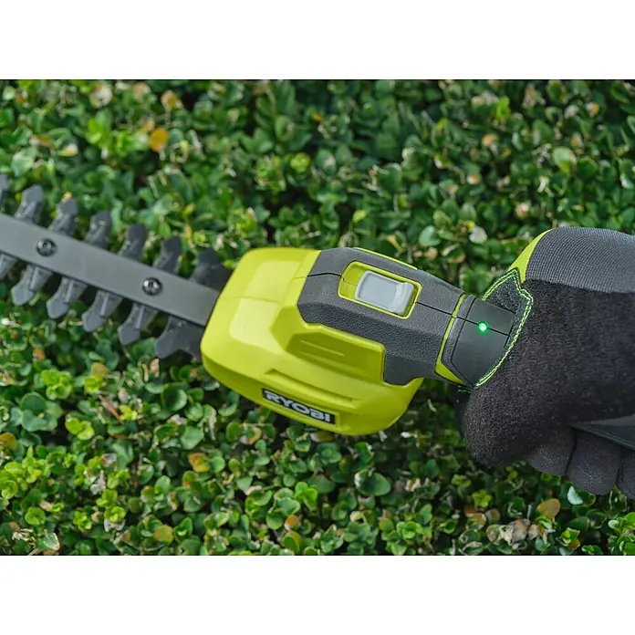 Ryobi Akku-Gras- & Strauchschere RY4CGSA-120 - Li-Ionen, 1 Akku - Nahaufnahme einer behandschuhten Person, die eine limettengrüne und graue Akku-Heckenschere mit grünem Licht hält.