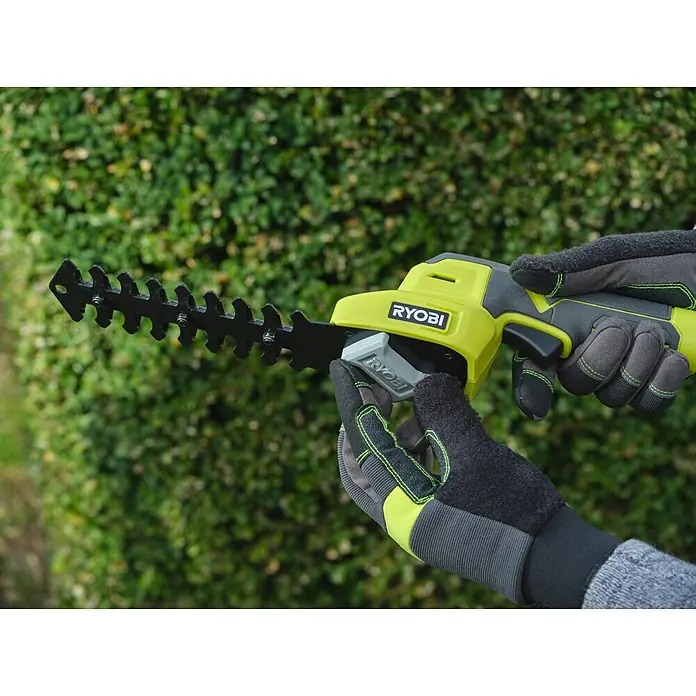 Ryobi Akku-Gras- & Strauchschere RY4CGSA-120 - Li-Ionen, 1 Akku - Gelbe und graue Ryobi Heckenschere mit schwarzen Klingen, gehalten von Händen in grau-grünen Arbeitshandschuhen.