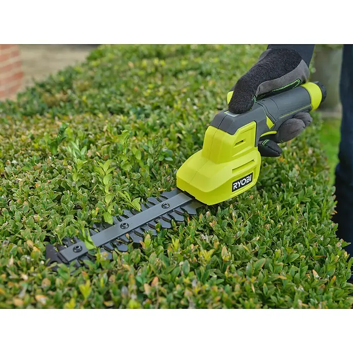 Ryobi Akku-Gras- & Strauchschere RY4CGSA-120 - Li-Ionen, 1 Akku - Limettengrüner und dunkelgrauer Ryobi Heckenschneider, von einer behandschuhten Hand an einer grünen Hecke verwendet.