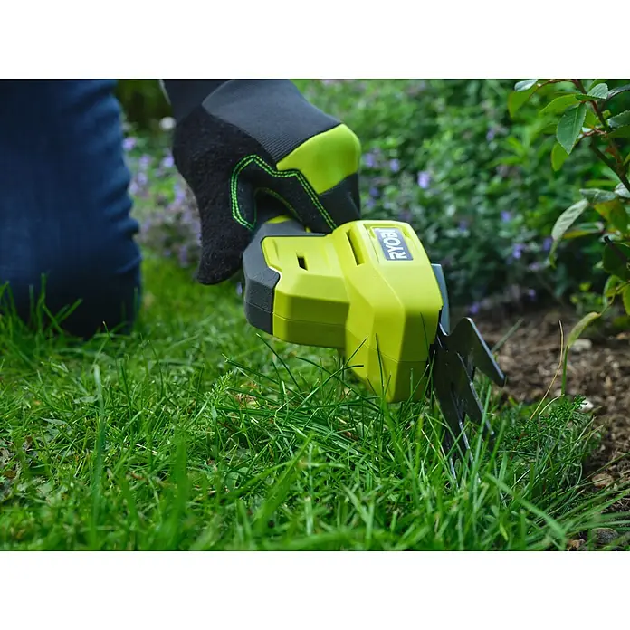 Ryobi Akku-Gras- & Strauchschere RY4CGSA-120 - Li-Ionen, 1 Akku - Eine Person mit schwarzem und limettengrünem Handschuh trimmt Rasenkanten im Garten mit einer Ryobi Akku-Grasschere.