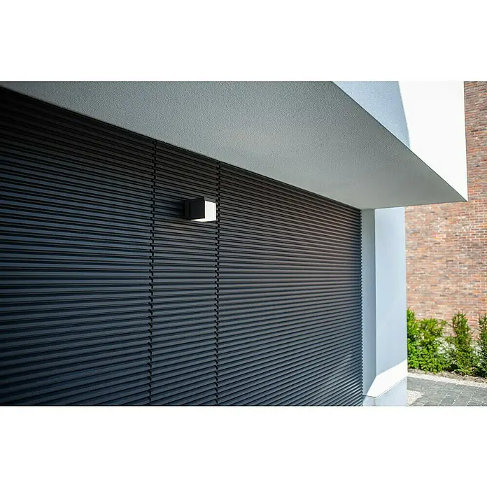 Lutec Aplique de pared LED Cuba - L x An x Al: 116 x 100 x 148 mm, Blanco neutro, Temperatura del color: 4.000 K, 500 lm - Revestimiento de pared exterior de lamas horizontales gris oscuro con una moderna lámpara de pared cuadrada iluminada.