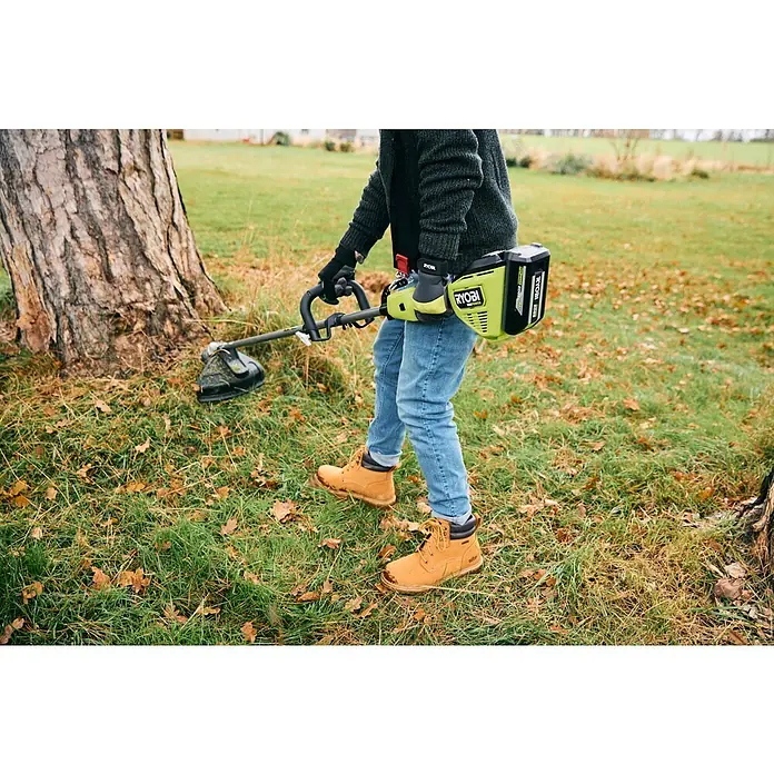 Ryobi Max Power Akku RY36BET40A - 36 V, 4 Ah, Li-Ionen - Eine Person bedient einen limettengrünen und schwarzen Ryobi Akku-Rasentrimmer zum Grasschneiden an einem Baum.