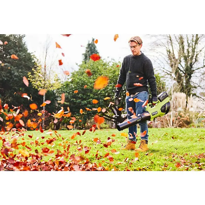 Ryobi Max Power Akku RY36BET80A - 36 V, 8 Ah, Li-Ionen - Ein Mann in einem Garten benutzt einen grün-schwarzen Ryobi Laubbläser, um Herbstlaub vom Rasen zu entfernen.
