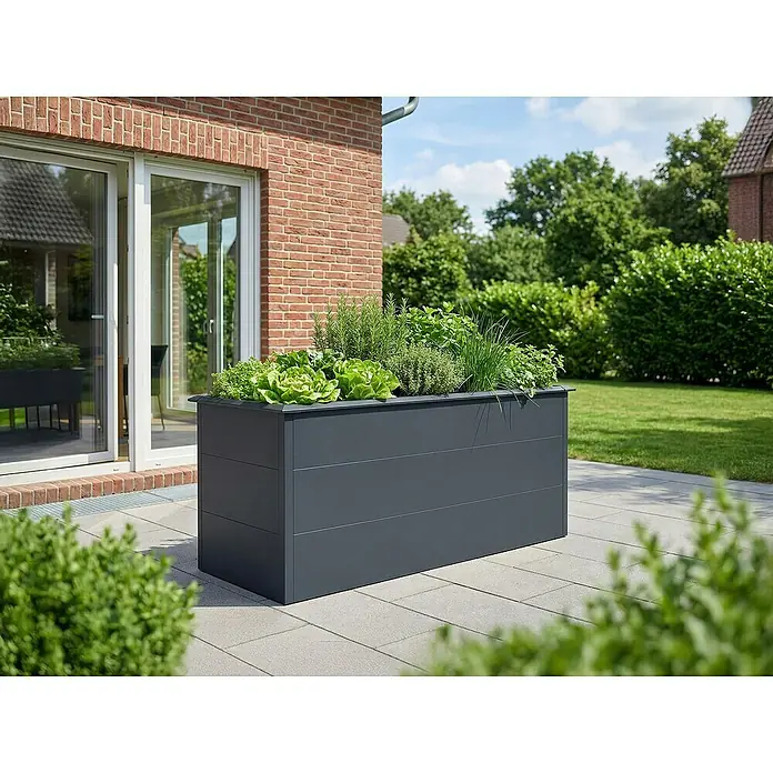Plats Hochbeet - 150 x 75 x 77 cm, Metall, Anthrazit - Ein großes, dunkelgraues Hochbeet gefüllt mit verschiedenen grünen Kräutern und Salat steht auf einer Terrasse neben einem Haus.