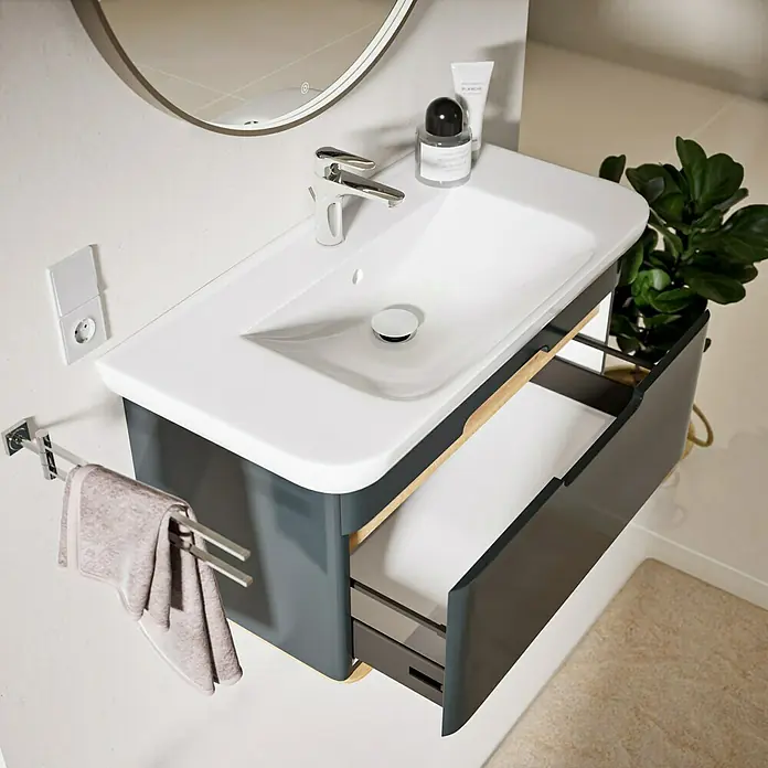 VitrA Sento Badmöbel-Set Sento - 98 cm, Anthrazit, Griffmulde - Modernes weißes Waschbecken mit dunkelgrauem Unterschrank, teils geöffneter Schublade mit Holzdekor und Chromarmatur im Badezimmer.