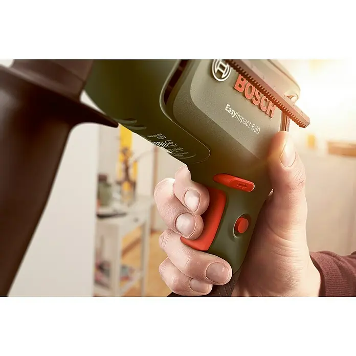 Bosch Schlagbohrmaschine EASYIMPACT 630 - 630 W, Schnellspannbohrfutter - Hand hält eine grüne Bosch EasyImpact 630 Bohrmaschine mit roten Akzenten, einsatzbereit in heller Innenumgebung.