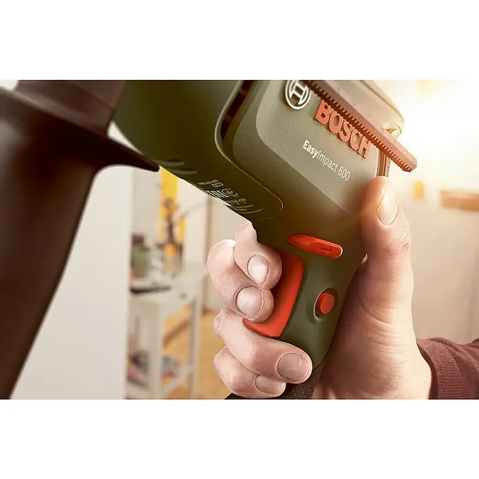 Bosch Schlagbohrmaschine EASYIMPACT 600 - 600 W - Eine Hand hält eine olivgrüne Bosch EasyImpact 600 Schlagbohrmaschine mit roten Akzenten, einsatzbereit.