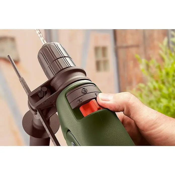 Bosch Schlagbohrmaschine EASYIMPACT 600 - 600 W - Nahaufnahme einer Hand, die eine grün-braune Bosch-Bohrmaschine mit Bohrer und Tiefenanschlag vor unscharfem Hintergrund bedient.