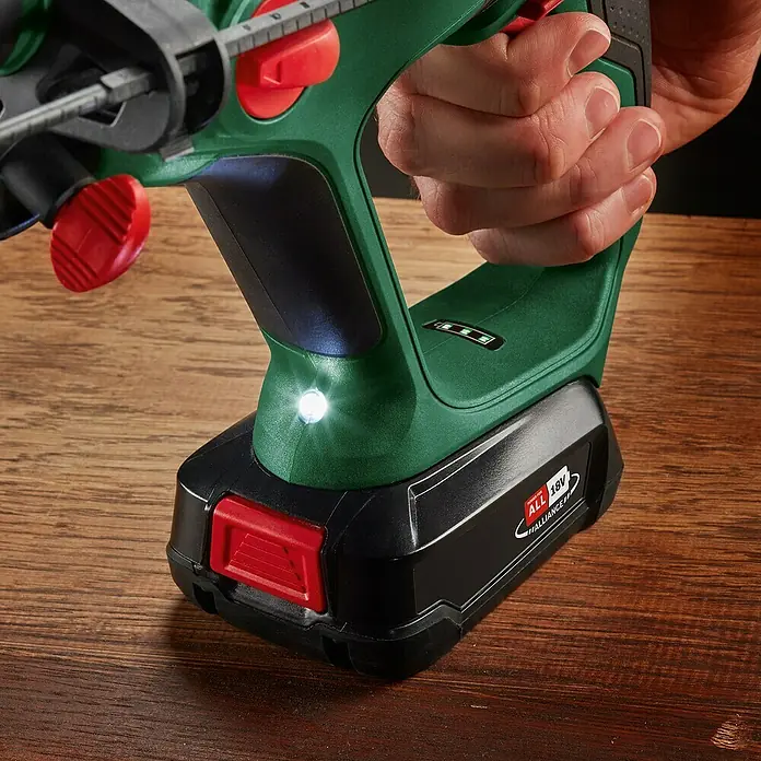 Bosch Power for All 18V Akku-Kombihammer UniversalHammer 18V - 18 V, Ohne Akku, 2 J, Mit Schnellspannbohrfutter - Hand hält grünen und schwarzen Akku-Bohrschrauber mit LED-Licht und 18V-Akku auf Holz.