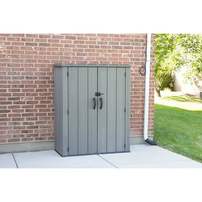 Lifetime Geräteschrank - Außenbreite inkl. Dachüberstand: 136 cm, Außentiefe inkl. Dachüberstand: 70 cm, Kunststoff, Dunkelgrau - Das graue Lifetime-Gartenschrank ist eine großartige Stauraumlösung für den Außenbereich, die an einer Ziegelmauer aufgestellt ist.