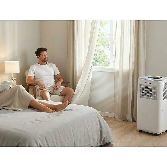 Purline Aire acondicionado portátil Cooly - 2.640 W, Tamaño de la estancia: 20 m², Blanco - Aire acondicionado portátil blanco Purline con una luz azul en la parte superior, en un dormitorio.