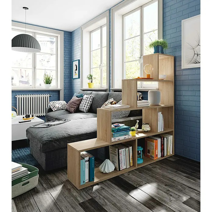 Estantería de madera Klum - L x An x Al: 29 mm x 145 cm x 145 cm, Roble Canadian - Estantería y separador de ambientes de madera clara escalonada en un salón moderno, con libros y objetos decorativos.