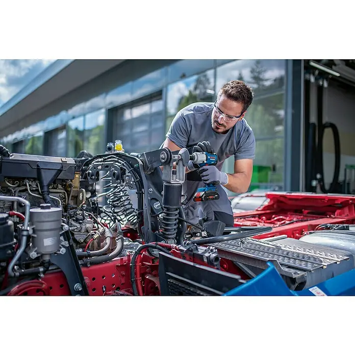 Bosch Professional AMPShare 18V Akku-Drehschlagschrauber PRO GDS 18V-450 HC - 18 V, Ohne Akku, 450 Nm - Mann mit Schutzbrille benutzt einen blau-schwarzen Bosch Akku-Schlagschrauber mit rotem Akku an einem LKW-Motor.