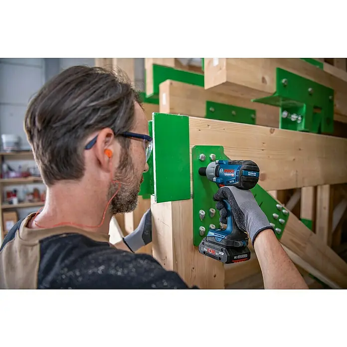 Bosch Professional AMPShare 18V Akku-Drehschlagschrauber PRO GDS 18V-450 HC - 18 V, Ohne Akku, 450 Nm - Blauer und schwarzer Bosch Schlagschrauber wird verwendet, um einen Bolzen in einen Holzbalken zu befestigen.