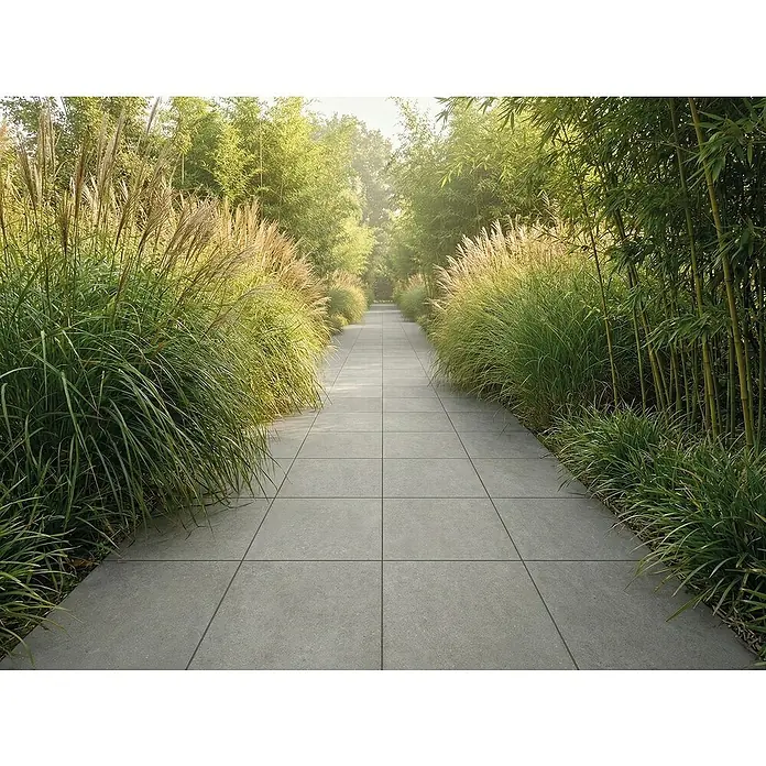 Terrassenfliese Portland - 60 x 60 x 2 cm, Londra, Matt - Graue Pflasterfliesen bilden einen Gartenweg, gesäumt von Gräsern und Bambus, der in die Ferne führt.