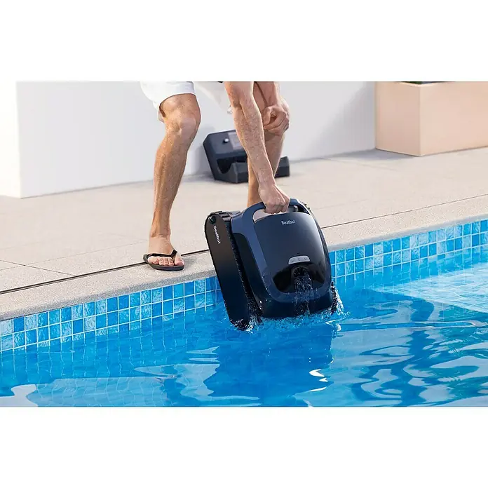Beatbot Poolroboter AquaSense 2 - Akkubetrieben, Passend für: Pools bis 300 m² Grundfläche, Filterleistung: 20.800 l/h - Dunkelblauer Beatbot Poolreinigungsroboter wird von einer Person in einen gefliesten Pool gesenkt.