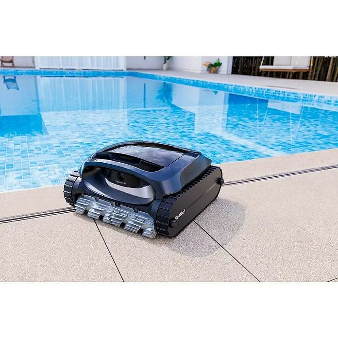 Beatbot Poolroboter AquaSense 2 - Akkubetrieben, Passend für: Pools bis 300 m² Grundfläche, Filterleistung: 20.800 l/h - Ein dunkelgrauer Roboter-Poolreiniger mit grauen Raupenbändern am hellen Beckenrand, bereit zum Einsatz im blau gefliesten Pool.