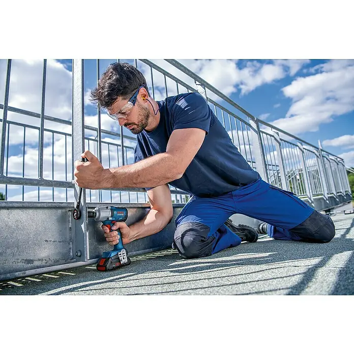 Bosch Professional AMPShare 18V Akku-Drehschlagschrauber GDS 18V-450 HC - 18 V, 2 Akkus, 5 Ah, 450 Nm, 2 Akkus, L-Boxx - Ein Mann verwendet einen blauen Bosch Akku-Schlagschrauber, um eine Schraube an einem Metallgeländer festzuziehen.