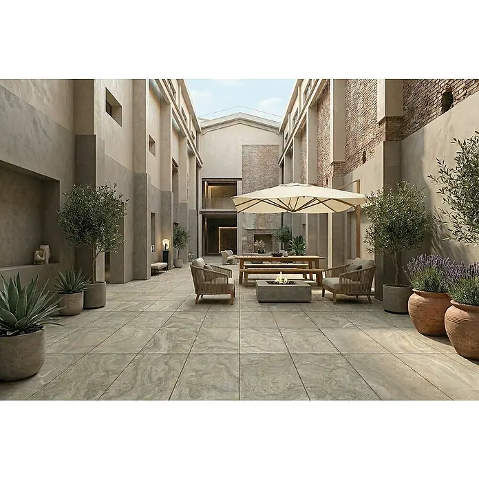 Terrassenfliese Porcea - 60 x 90 x 2 cm, Eramosa, Matt - Große, hellfarbene marmorierte Terrassenfliesen bilden den Boden eines Innenhofs mit Sitzgelegenheiten und Pflanzen.