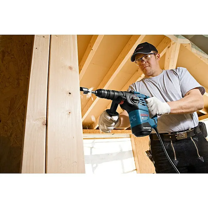 Bosch Professional Bohrhammer GBH 3-28 DFR - 800 W, 3,1 J, SDS-Plus-Aufnahme, Inkl. L-Boxx - Mann bohrt mit einem blau-schwarzen Bosch Bohrhammer in einen Holzbalken.