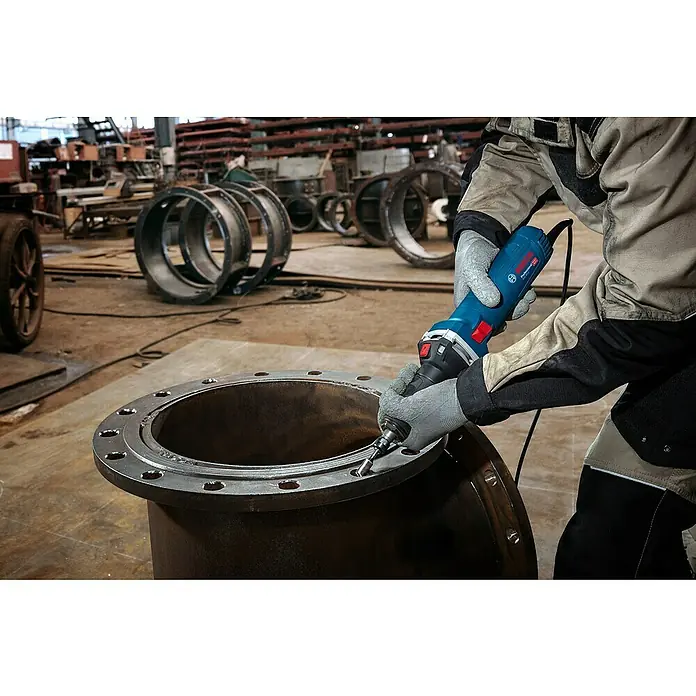 Bosch Professional Geradschleifer GGS 30 LS - 750 W, Leerlaufdrehzahl: 7.000 U/min - 33.000 U/min - Person mit Handschuhen verwendet einen blauen Bosch Geradschleifer, um einen großen Metallflansch zu glätten.