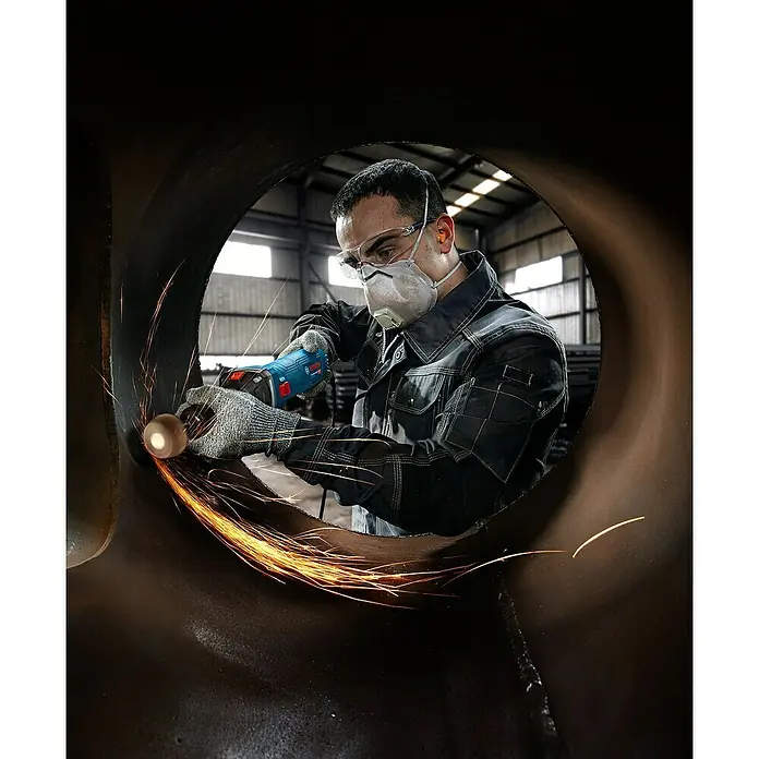 Bosch Professional Geradschleifer GGS 30 LS - 750 W, Leerlaufdrehzahl: 7.000 U/min - 33.000 U/min - Blauer Bosch Geradschleifer, von einem Arbeiter zum Schleifen von Metall verwendet, erzeugt Funken.