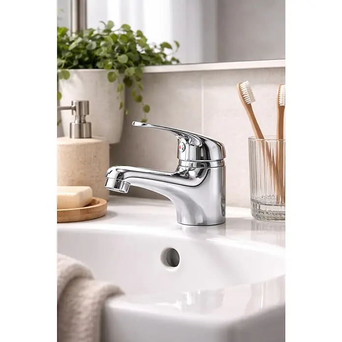 Rousseau Memphis Grifo de lavabo - Cromo, Resplandeciente - Grifo de baño cromado pulido sobre un lavabo blanco, con jabón y cepillos de dientes cerca.