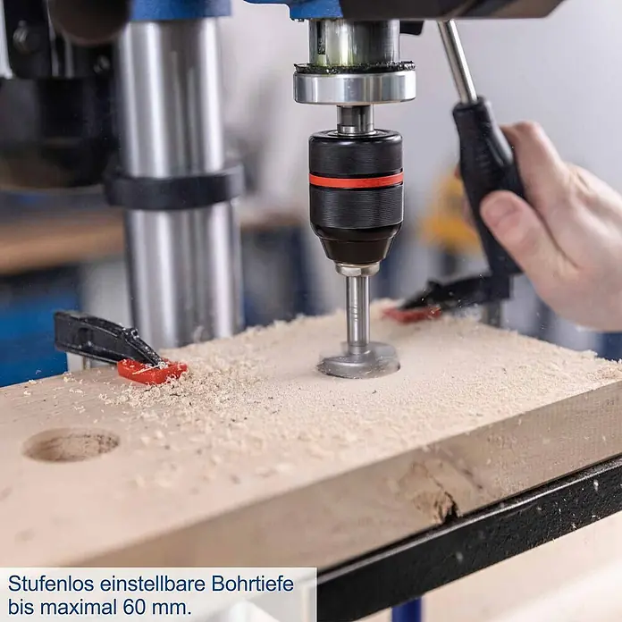 Scheppach Tischbohrmaschine TBM250 Vario - 600 W, Leerlaufdrehzahl: 1.490 U/min, Spannweite Bohrfutter: 3 mm - 13 mm - Ständerbohrmaschine mit schwarzem Futter und Holzbohrer bohrt ein Loch in helles Holzbrett.