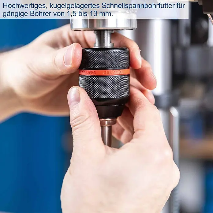 Scheppach Tischbohrmaschine TBM250 Vario - 600 W, Leerlaufdrehzahl: 1.490 U/min, Spannweite Bohrfutter: 3 mm - 13 mm - Hände stellen ein schwarzes Schnellspannbohrfutter mit orangefarbenem Ring ein, passend für Bohrer von 1,5 bis 13mm.