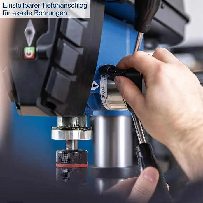 Scheppach Tischbohrmaschine TBM250 Vario - 600 W, Leerlaufdrehzahl: 1.490 U/min, Spannweite Bohrfutter: 3 mm - 13 mm - Nahaufnahme einer blauen und schwarzen Bohrmaschine. Eine Hand verstellt den einstellbaren Tiefenanschlag mit schwarzem Knopf und Skala für präzise Bohrungen.