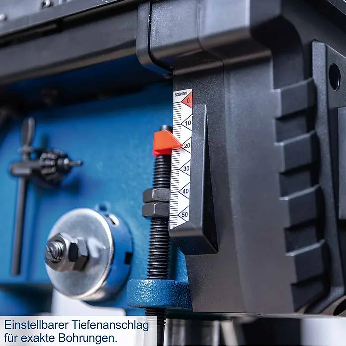 Scheppach Tischbohrmaschine TBM200 - 400 W, 550 U/min - 2.600 U/min, Spannweite Bohrfutter: 1,5 mm - 13 mm - Nahaufnahme eines einstellbaren Tiefenanschlags mit weißer Millimeterskala und rotem Anzeiger an einer blau-schwarzen Maschine für präzises Bohren.