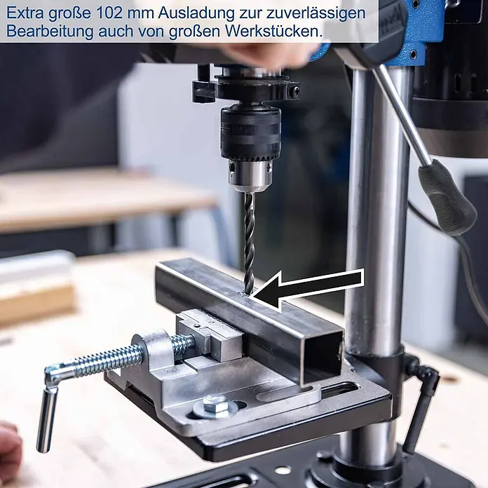 Scheppach Tischbohrmaschine TBM200 - 400 W, 550 U/min - 2.600 U/min, Spannweite Bohrfutter: 1,5 mm - 13 mm - Eine Bohrmaschine mit großer 102 mm Ausladung bohrt ein Loch in ein Metallprofil, das von einem Schraubstock gehalten wird.
