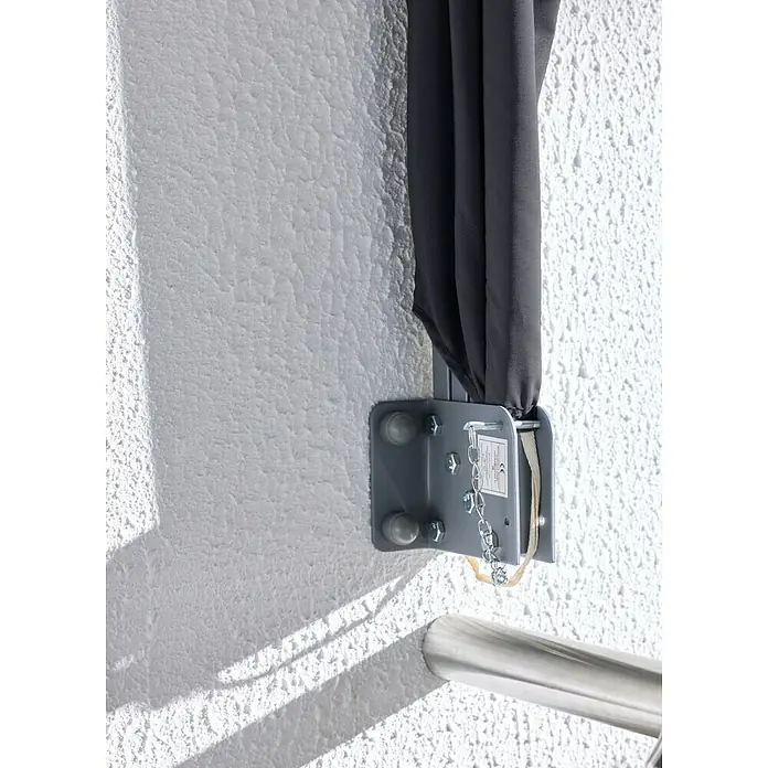 Sunfun Balkonfächer - Anthrazit, 1,4 x 1,4 m - Graue Metallhalterung an einer strukturierten weißen Wand, die dunkelgrauen Stoff hält. Darunter ist ein Metallgeländer zu sehen.