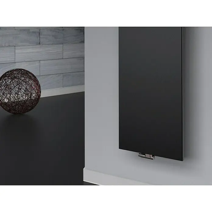 Szagato Designheizkörper Manhattan 3 - B x H: 470 x 1.800 mm, Wärmeleistung bei Vorlauftemperatur von 75 °C (D: 50): 1.118 W, Schwarz, Mit 2 Handtuchhalter (50 mm) - Ein modernes schwarzes Heizpaneel an einer grauen Wand, mit einem dekorativen Element auf einer dunklen Oberfläche im Hintergrund.