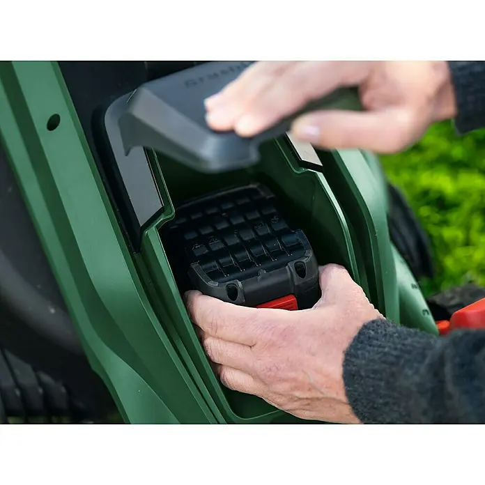 Bosch Power for All 18V Akku-Rasenmäher ROTAK18V-32 - Ohne Akku, Schnittbreite: 32 cm - Hände führen einen schwarzen Akku mit rotem Auslöseknopf in ein dunkelgrünes Elektrowerkzeug ein.