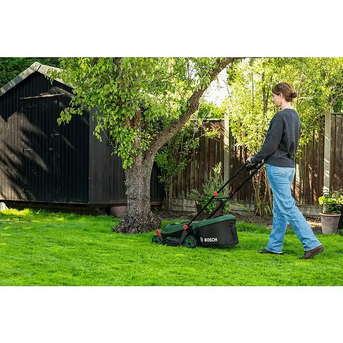 Bosch Power for All 18V Akku-Rasenmäher ROTAK18V-34 - Ohne Akku, Schnittbreite: 34 cm - Grüner und schwarzer Bosch Rasenmäher, der von einer Frau zum Mähen eines üppigen grünen Rasens verwendet wird.
