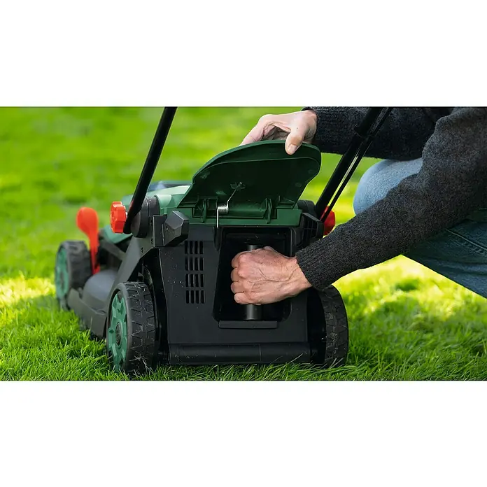 Bosch Power for All 18V Akku-Rasenmäher ROTAK18V-34 - Ohne Akku, Schnittbreite: 34 cm - Eine Person öffnet das Fach des grün-schwarzen Elektromähers, um eine Komponente zu entnehmen.