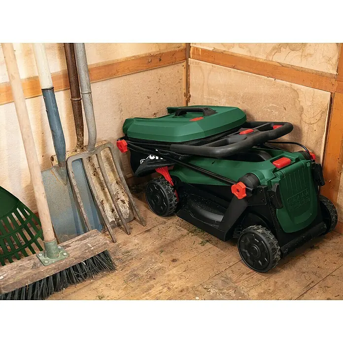 Bosch Power for All 18V Akku-Rasenmäher ROTAK18V-32 - Ohne Akku, Schnittbreite: 32 cm - Zusammengeklappter grüner Rasenmäher in einem Schuppen mit Gartengeräten.