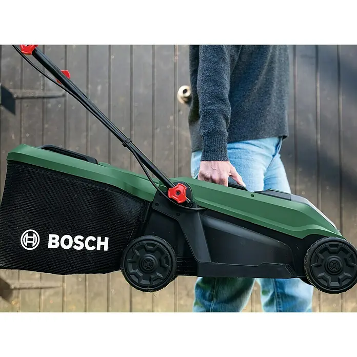 Bosch Power for All 18V Akku-Rasenmäher ROTAK18V-32 - Ohne Akku, Schnittbreite: 32 cm - Eine Person trägt einen grün-schwarzen Bosch Rasenmäher mit Fangkorb.
