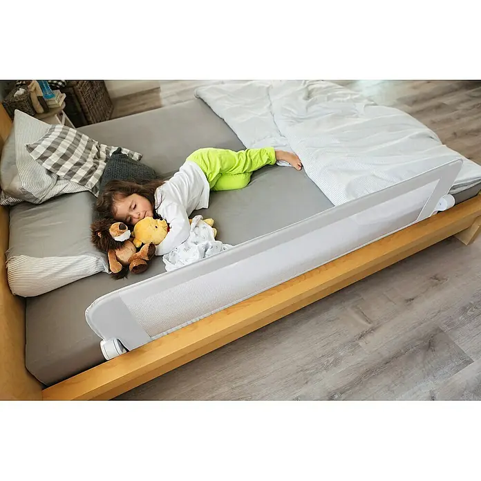 Abus Bettgitter Eric - Länge: 150 cm - Das Bild zeigt ein weißes Bettgitter, das am Bett befestigt ist, um zu verhindern, dass Kinder herausfallen, während ein Kind darin schläft.