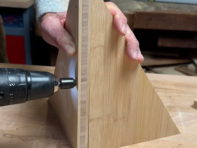 2 Holzplatten in Dreieck-Form werden aneinander geschraubt