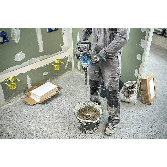 Bosch Professional Akku-Rührwerk GRW 18V-120 - 18 V, Anzahl Akkus: Ohne Akku - Person mischt grauen Mörtel in einem schwarzen Eimer mit einem blau-schwarzen Bosch Rührwerk auf einer Baustelle.