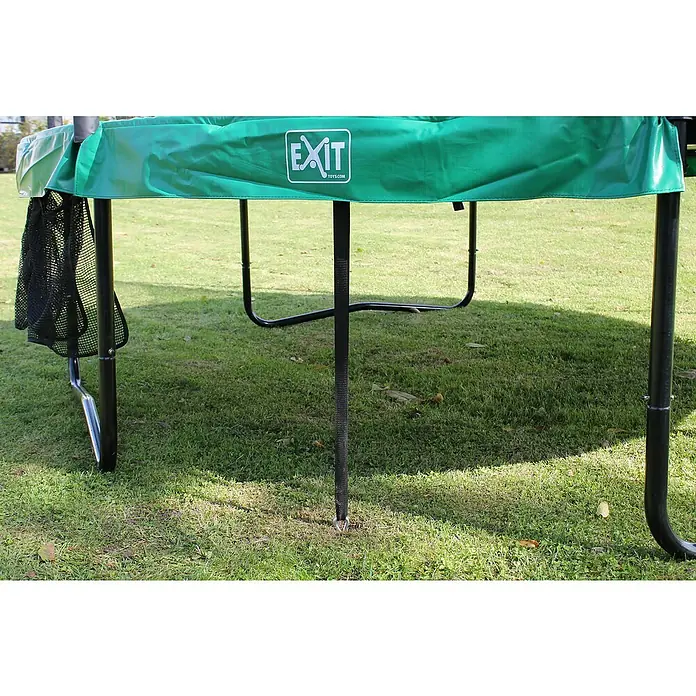 Exit Toys Trampolin-Verankerungsset - 4 Stk., Stahl - Grüner Trampolin-Sockel mit schwarzen Beinen und Netztasche, mit Erdspirale im Gras verankert.