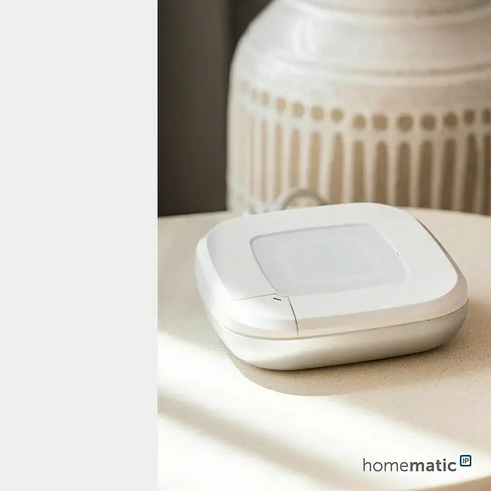 Homematic IP Starter-Set 2x Heizkörperthermostat Pure mit Access Point 2 HmIP-SK28 - Weiß - Weißer Homematic IP Smart-Home-Sensor auf heller Oberfläche, mit verschwommenem Hintergrund.
