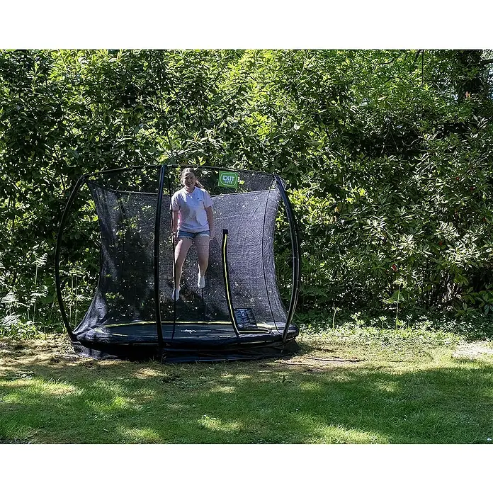 Exit Toys Trampolin Silhouette Bodentrampolin mit Sicherheitsnetz - Durchmesser: 305 cm, Rosa - Eine junge Frau springt auf einem schwarzen EXIT Toys Trampolin mit Sicherheitsnetz.
