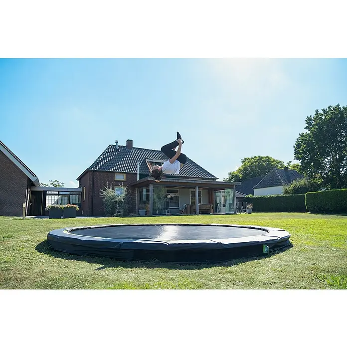 Exit Toys Trampolin Silhouette Sports - Durchmesser: 366 cm, Schwarz - Ein schwarzes Bodentrampolin mit Polsterung, auf dem eine Person einen Salto macht.