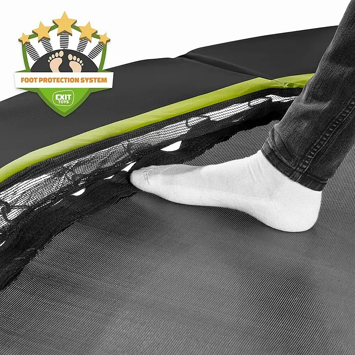 Exit Toys Trampolin Silhouette - Durchmesser: 183 cm, Schwarz - Fuß in weißer Socke auf schwarzer Trampolinmatte, grünem Polster und Sicherheitsnetz, zeigt das „Foot Protection System“.