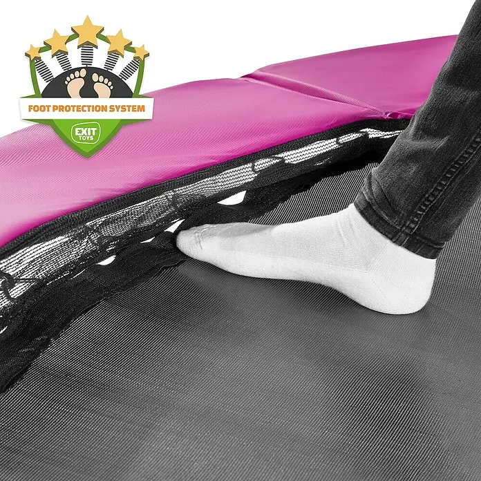 Exit Toys Trampolin Silhouette - Durchmesser: 183 cm, Rosa - Ein Fuß in weißer Socke auf Trampolinmatte, neben pinker Schutzpolsterung und schwarzer Federabdeckung, zeigt das 'Fußschutzsystem'.